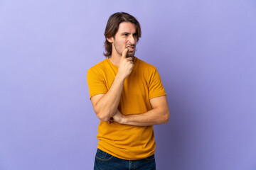 Young handsome man isolated on purple background nervous and scared