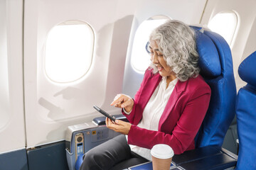 An adult woman sits by the window on a passenger plane, eagerly traveling abroad. She gazes at the...
