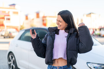 Young woman at outdoors holding car keys at outdoors celebrating a victory