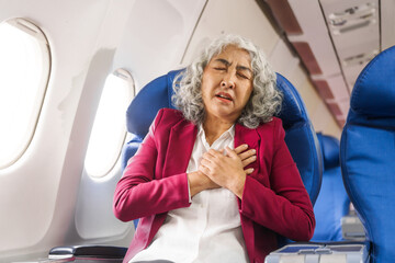 A mature woman sits by the window on a passenger plane, traveling abroad. She looks unwell, experiencing a headache, nausea, and vomiting, which dampens her travel excitement.