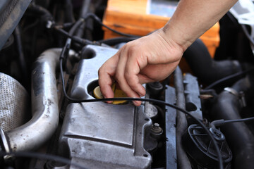 Obraz premium Change of oil. A man's hand opens or closes the oil filler cap. Changing the oil in a diesel car engine. Car maintenance. Old car. The mechanic inspects the car