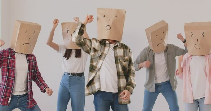 Group of activist people wearing paper masks depicting negative emotions in protest, providing strike. They are advocating for justice and democracy, expressing discontent in rebel or riot.