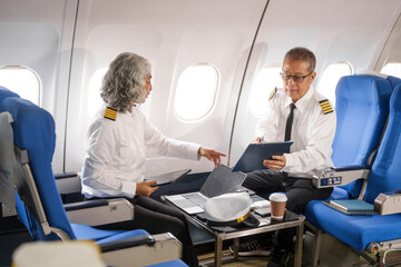 Mature male and female pilots meet inside an airplane, holding hands. Their gesture signifies...