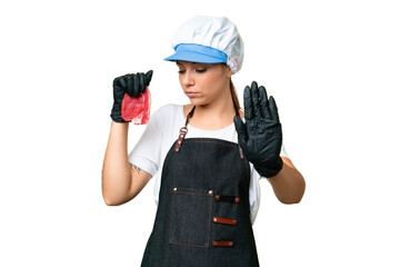 Butcher woman wearing an apron and serving fresh cut meat over isolated chroma key background making stop gesture and disappointed