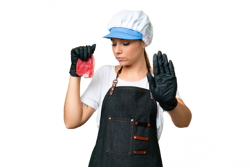 Butcher woman wearing an apron and serving fresh cut meat over isolated chroma key background making stop gesture and disappointed