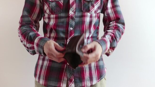 resigned man shows wallet and it is empty, he's wearing a checkered shirt and he stays on a white background
