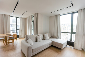 Bright living room interior with large sofa and oak wooden floor. Concept of minimalist design. Comfortable place for meeting.