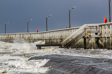 Beautiful seascape : North Sea waves rolling onto wave breaker and old wooden pier