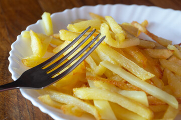 Fried potatoes on a white plate close-up. Fried potatoes on a plate with a fork