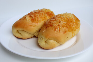 Two baked bread with grated cheese on top, on white plate, isolated on white background