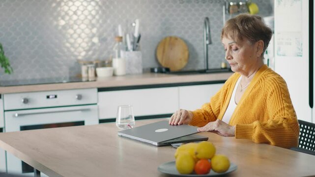 A mature woman finishing her workday at home. A senior businesswoman closes a laptop and reclining in a chair.