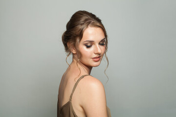 Fototapeta premium Fashionable glam woman fashion model with makeup and updo hairstyle on gray studio background