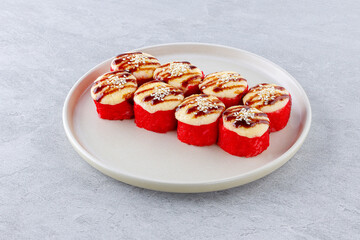 Baked sushi roll with salmon in caviar, garnished with unagi sauce and sesame seeds