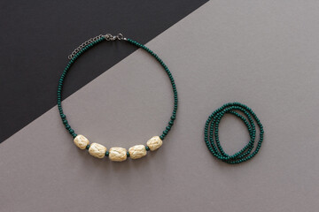 Straw and bead necklace and green beaded bracelet. Green beaded. Gray background