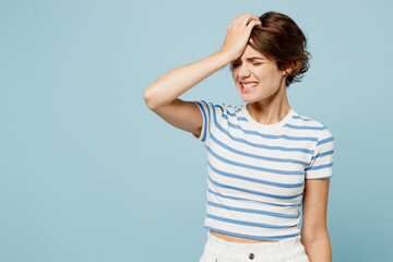 Young sad woman she wear striped t-shirt casual clothes put hand on face facepalm epic fail mistaken omg gesture isolated on plain pastel light blue cyan background studio portrait. Lifestyle concept
