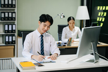 Young businessman working at office with laptop, tablet and taking notes on the paper..