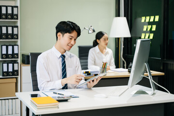 Young businessman working at office with laptop, tablet and taking notes on the paper..