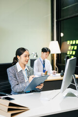 Asian female office worker business suits smiling at camera with working notepad, tablet and laptop documents .
