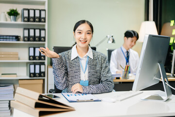 Asian female office worker business suits smiling at camera with working notepad, tablet and laptop documents .