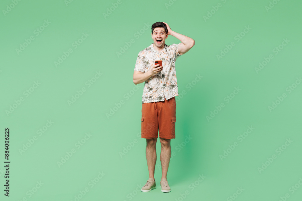 Sticker Full body young shocked surprised Caucasian man he wear white shirt casual clothes hold head use mobile cell phone isolated on plain pastel light green background studio portrait. Lifestyle concept.