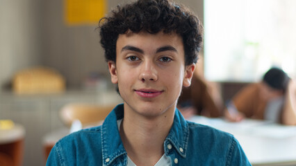 Portrait indoors happy smiling carefree Caucasian pupil teen boy teenager student guy teenage man male schoolboy looking at camera in class lesson classroom education study school university smile