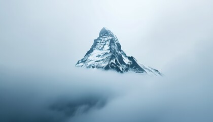 Majestic snow-covered mountain peak emerging through thick clouds, serene winter landscape with misty atmosphere and a sense of tranquility.