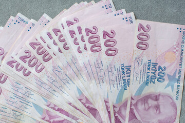 A thick stack of Turkish lira is laid out on a gray velvet table, ready to be counted, 200 Turkish...