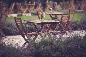 Coffeehouse cafe restaurant terrace. Wooden chairs and tables with flowers in park. Outdoor terrace. Shallow focus. Old fashioned empty cafe terrace with vintage chairs and tables. Loft style cafe.