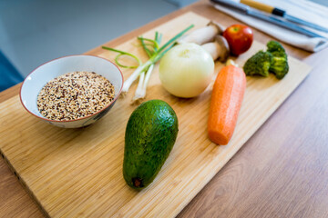 Cutting board with ingredients for preparing healthy quinoa bowl with avocado