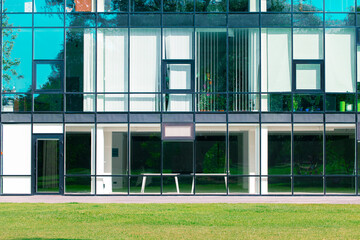 modern building real estate office architecture exterior facade glass windows and walls object background with grass lawn foreground