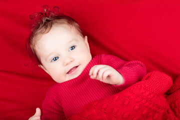 Little baby on red blanket in bed