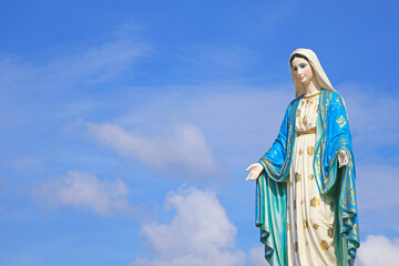 Fototapeta premium Gorgeous Sculpture of Saint Mary, the Holy Mother of God on Sunlight Sky Background