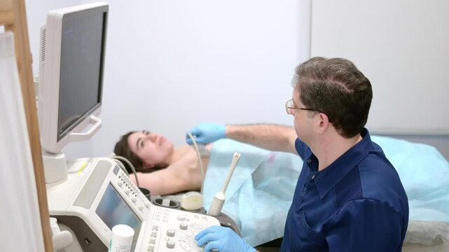 Mammologist doctor examines a woman breasts and lymph nodes using ultrasound. Mammography and ultrasound scanning are main methods of instrumental diagnosis of mammary glands. Breast cancer awareness