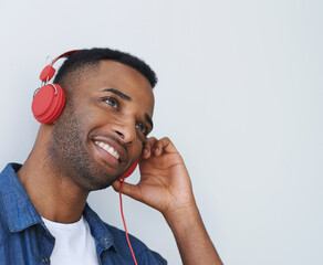 Happy man, headphones and listening with music for podcast, audio or radio on a white studio background. Young male person with smile or headset in wonder for streaming choice, sound or song album