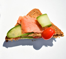 Close-up sandwich with salmon fish, tomato, cucumber, cheese on white background,  top view