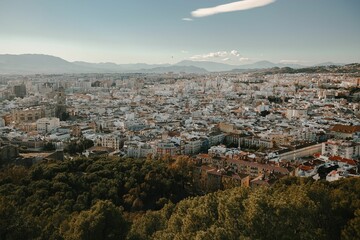 Aerial view of Malaga cityscape with mountains in the background and blue sky.
