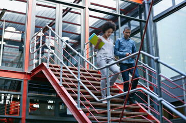 Fototapeta premium Walking, stairs and business people in office for meeting, appointment or project presentation. Discussion, media agency and employees with paperwork for collaboration, partnership or conversation