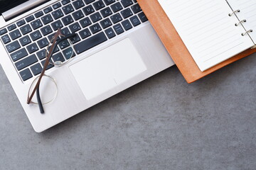 リング式のシステム手帳を開いて、ノートパソコンでデスクワークをしているイメージ
