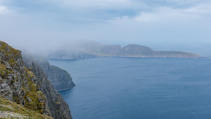 Obraz premium A misty view from the clifftops overlooking the dramatic coastline of Northern Norway. Nordkap or North Cape