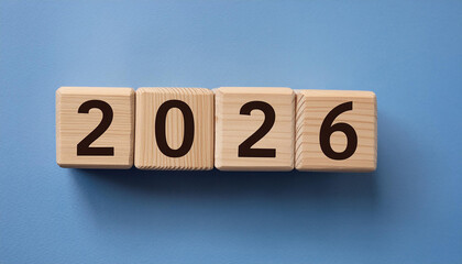 Wooden cubes with number 2026 on blue backdrop. New year. Wood blocks. Close-up. Flat lay.