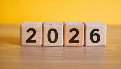 Wooden cubes with number 2026 on yellow backdrop. New year. Wood blocks. Close-up.