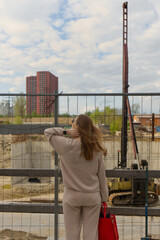 The image depicts an individual observing a construction site, capturing the juxtaposition of urban development and daily life. 