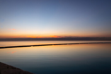 Naklejka premium Sunset at Dead Sea looking form Jordan towards Israel with a swimming pool in the foreground
