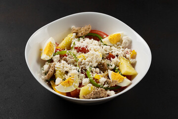 Fresh salad - tomatoes, eggs, feta cheese and paprika. Dark background.