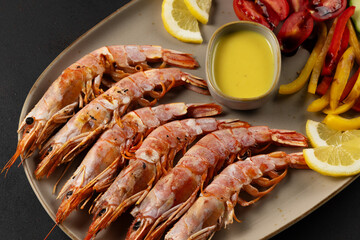 Fried shrimps on plate with fresh vegetables and lemon slice. Seafood background.