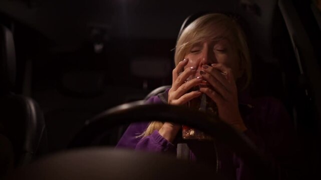 Portrait of blonde woman sitting in passenger compartment of car in drive-in cinema enjoys watching movie, emotionally screams in fear, covers face with hand, reaction to horror adrenaline from fright