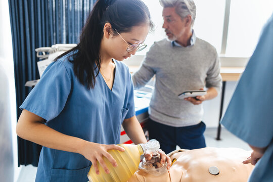 Asian nursing student learns how to use a bag valve mask on a patient simulator