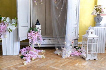 White vintage wardrobe with wooden lanterns decorated blooming pink wisteria flowers. Elegant wedding decor photo zone. Flowering of Purple Wisteria close-up. Wedding decoration	
