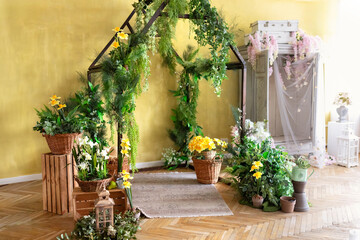 Interior of a wooden greenhouse. Wooden arch in the form of a house covered plants and flowers. Wooden archway decorated green plants. Rectangular wooden arch made and flowers for wedding decoration.	