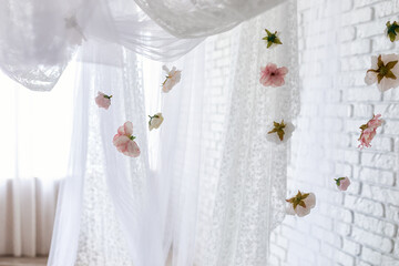 White lace texture curtains with floral abstract pattern with spring flowers levitate. Summer pink peonies flowers levitating, hanging flowers on a white background, copy space. Template, mockup.	
